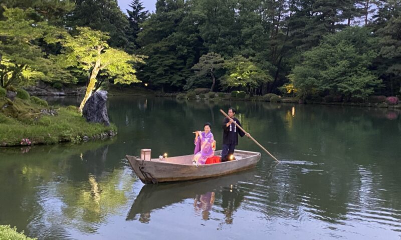 兼六園・霞ヶ池に浮かべた小舟の上で横笛を演奏する女性
